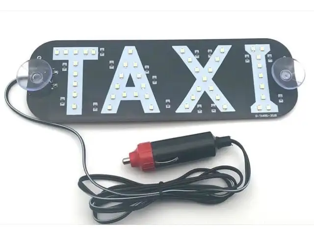 An illuminated LED taxi sign with suction cups and a cigarette-lighter plug lead, lit white against a black panel.